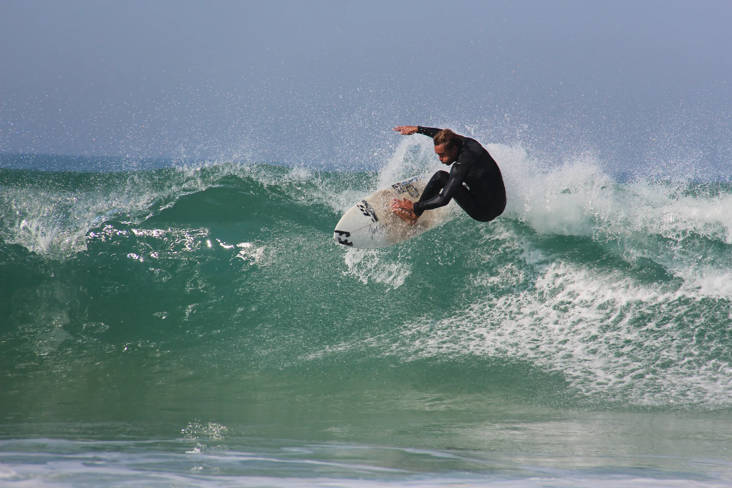 Surfeur en plein virage sur une vague verte
